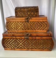 Front view of the three stacked wood and woven boxes showing size difference and decorative patterns
