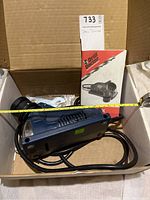 Side view of the Drill Doctor 350X with manual and some parts in a cardboard box.