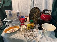 Various kitchen items displayed on a table including kettle, toaster, glassware, trays, mugs, and storage containers