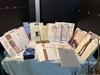 Photo showing full lot of 20 packages of ladies nylons from multiple brands and colors, arranged on a table with ruler for size reference.