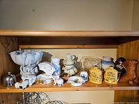 Overview of the full lot on a wooden shelf, showing lotus bowl, assorted pottery figurines, pottery boot candle holder, milk glass jar, silver ashtray, and other trinkets.