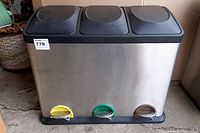 Front view of stainless steel bin showing three black lids and colored foot pedals