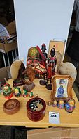 Photo showing a variety of decorative and collectible items including tiki mask, wooden African figurines, stone bookends, Russian nesting dolls, Asian trinket box and a Moscow Olympics plaque