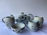 Full view of the teapot set including teapot, two cups, creamer, and sugar bowl with floral designs