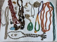 Overview photo showing multiple vintage costume jewelry pieces including assorted necklaces, pendants, and earrings in various colors and materials.