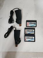 Photo of two Atari Videocade joystick controllers and three game cartridges on white surface