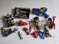 Assorted lot overview showing Valkyrie, boxed Power Lasr gun, blue ray gun, figures, small jets and robots