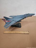 Side angle view of F-14 Tomcat metal model on stand showing detailed paint and markings with ruler for scale