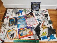 Full assortment of model jets and planes laid out on white surface with ruler for scale including boxed and loose diecast planes.