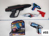 Top view showing six toy guns and original packaging arranged next to a ruler for size reference.