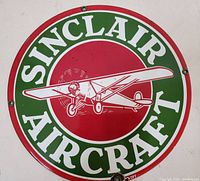 Front of the vintage Sinclair Aircraft porcelain sign showing green and red enamel with a white airplane illustration and text.