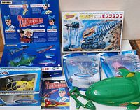 Full view of the collection showing boxed Matchbox Thunderbird Rescue Pack characters, multiple Thunderbird vehicles in packaging including blue Thunderbird 3 and yellow Thunderbird 4, a green Thunderbird 2 vehicle outside packaging, and a Thunderbirds VHS tape.