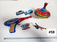 Overview of all six tin toys arranged on a white surface with measuring tape for scale.