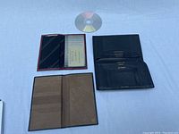 Red and black bill folds open to show credit card holders and compartments, with CD for size reference