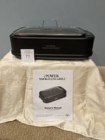 Front view of Power Smokeless Grill sitting on table with owner's manual in front.