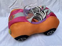 Side view of plush convertible car showing orange and pink colors with clear windshield and zebra pattern seats.