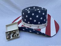 Photo showing American flag cowboy hat with six silver plated button covers in a small box.