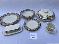 Top view of assortment including dinner plate, salad plate, casserole with lid, butter dish, and creamer showing garden harvest pattern.