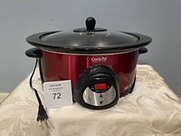 Red Rival Crock-Pot Oval Slow Cooker with digital timer and black handles on a table with power cord visible