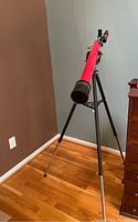 Photo of red Tasco telescope mounted on black tripod.