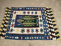 Full view of rectangular tribal patterned rug with green central motif and multicolor geometric borders laid flat on carpet.