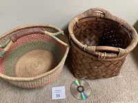 Photo showing top view of round-bottom basket with CD for size reference and square basket beside it.