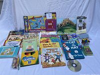 Overview of various kids items including books, crayons, markers, construction paper, card games, Rubik's Cube, and Pottery Barn bathtub grippers arranged on a surface.