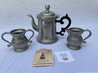 Full view of the kettle with creamer and sugar cup, including a small booklet and auction number card, showing the entire set.