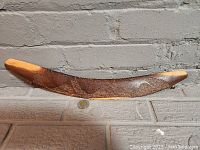 Front side of the hunting club showing detailed cassowary bird carvings and textured surface.