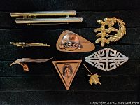 Photo showing a collection of eight assorted brooches in a black display case.