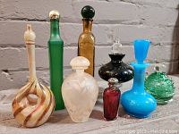 Eight vintage perfume bottles arranged in two rows showing colors, shapes, and stoppers.