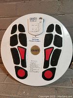 White circular foot platform with black and red textured foot pads, control panel with dials and indicator lights.