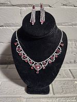 Photo showing necklace with clear and pink rhinestones in a formal pattern on a black velvet bust.
