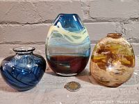 Three hand blown decorative glass pieces arranged side by side for size comparison and detail view.