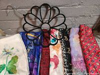 Photo of a pile of seven scarves folded together, showing various colors and patterns including floral and animal prints.