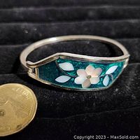 Close-up front view of the stamped Alpaca Mexico bracelet showing turquoise enamel inlay with white flower and leaves.
