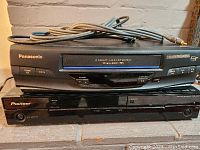 Front view of Panasonic VCR player on top of Pioneer HDD/DVD recorder, showing front panel buttons and labels