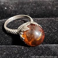 Close-up image of vintage women's amber ring with polished amber stone and twisted silver band.