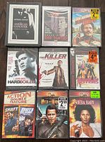 Top view of the first set of 9 DVDs showing titles including American Gangster, Die Hard, Jim Brown, Hard Boiled, The Killer, Chiens Tranquilles, Action Double Feature, Hell in the Pacific, Sheba Baby.