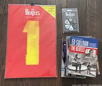 Photo showing the Beatles 2017 calendar, Beatles guitar picks pack, and five Beatles DVDs.