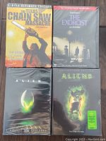 Four DVD movie cases arranged showing covers of The Texas Chainsaw Massacre, The Exorcist, Alien, and Aliens. All appear factory sealed and unopened.
