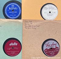 Four 78 RPM records in sleeves: Wynonie Harris “Good Rockin’ Tonight” (King), The Coasters “Young Blood” (Atco), Sam Cooke “I’ll Come Runnin’ Back to You” (Delta), Jimmy Reed “Baby, What’s On Your Mind?” (Vee Jay)