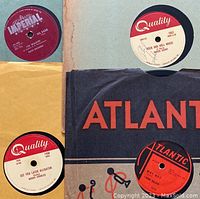 Four 78 RPM records: Imperial “I’m Walkin’” by Fats Domino; Quality “Rock and Roll Music” by Chuck Berry; Quality “See You Later Alligator” by Bobby Charles; Atlantic record in sleeve.