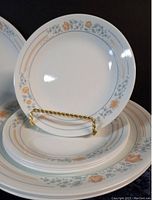 Stack of Apricot Grove appetizer and salad plates along with a displayed salad plate on a gold stand
