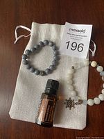 Two bead bracelets and a bottle of essential oil placed on a cloth pouch