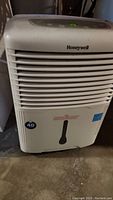 Front view of white Honeywell dehumidifier showing air vents, Honeywell logo, and water level indicator at bottom front.