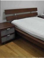 Queen bed frame with slat headboard, side table beside it, showing overall design and color.