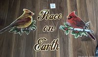 Photo of the complete set of the magnets on a floor wood surface showing the large male and female cardinals perched on holly leaves and berries with 'Peace on Earth' lettering.