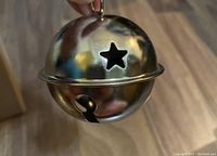 Close-up of a silver jingle bell with star cutouts and a hanging loop.