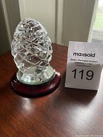 Crystal egg sculpture on wooden and glass mirror base with auction lot number card visible